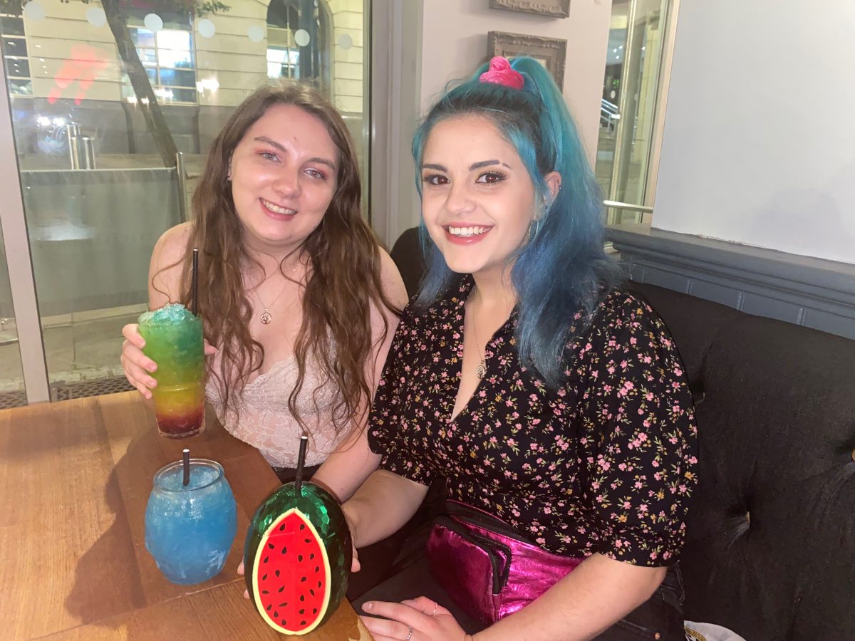 Maude and a friend sit inside a pub drinking alcohol
